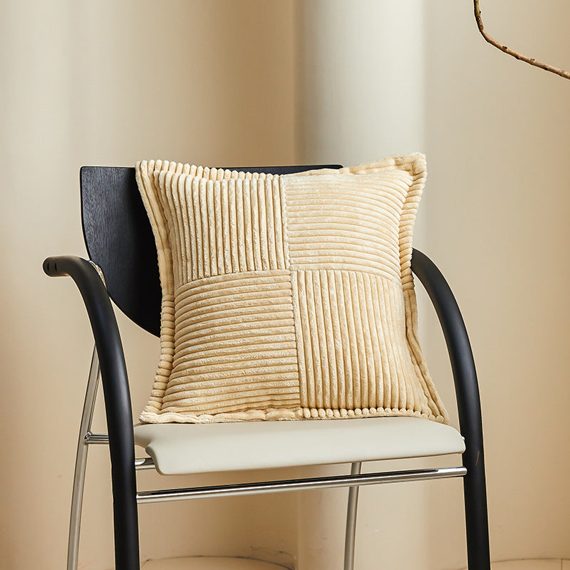 Housse de coussin en velours côtelé 45x45 cm beige posée sur un fauteuil